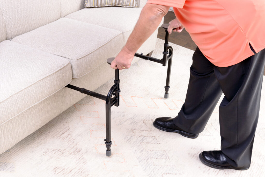 A man putting a EZ Stand-N-Go into her cream couch. 