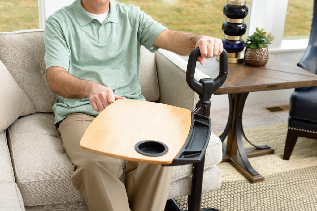 A man using his Stander Assist-A-Tray while sitting on his cream couch.
