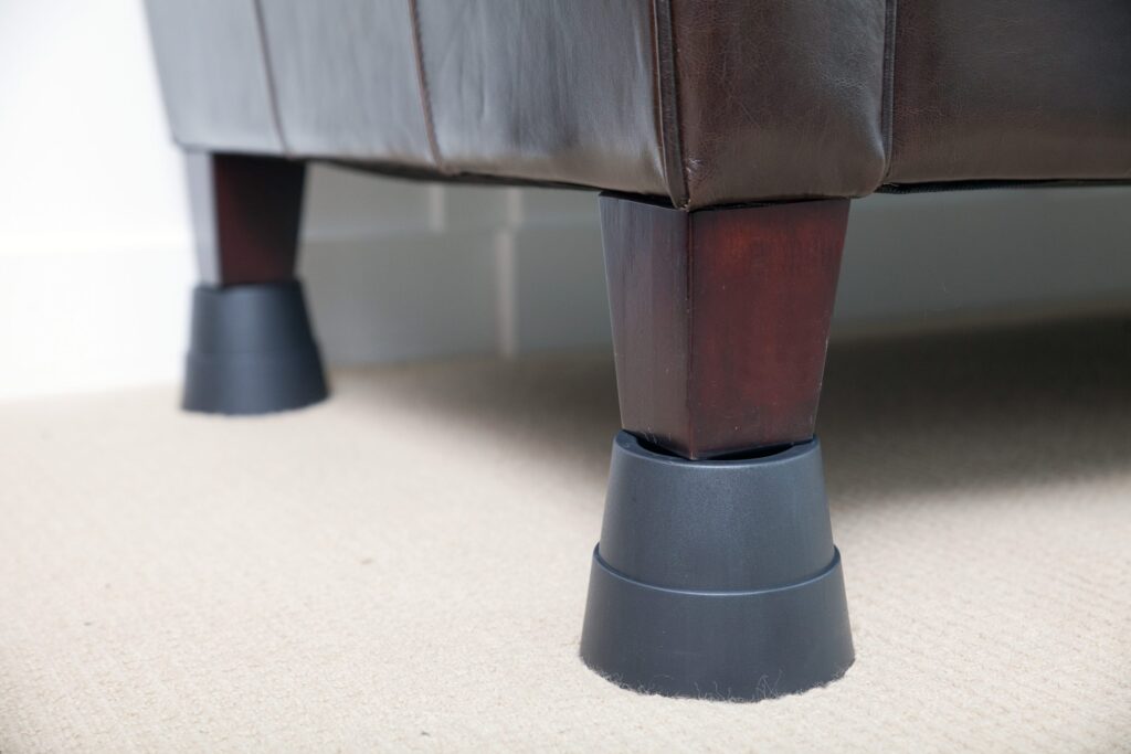 Two grey Stander Furniture Risers under brown chair legs. 