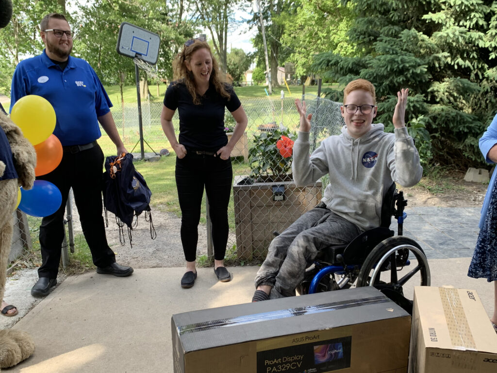 Young man seated in a manual wheelchair outdoors with arms lifted while receiving a Shine Experience