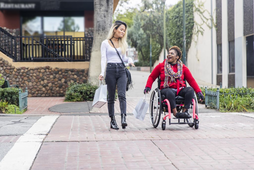 Woman in wheelchair crossing the street with friend